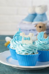 Photo of Beautifully decorated baby shower cupcakes for boy with cream and toppers on grey wooden table