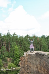 Photo of Young man on rock near lake and forest. Camping season