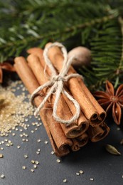 Photo of Cinnamon sticks and other spices on gray table, closeup