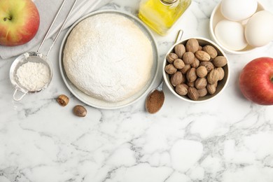 Photo of Raw dough, nutmeg seeds and other ingredients on white marble table, flat lay. Space for text