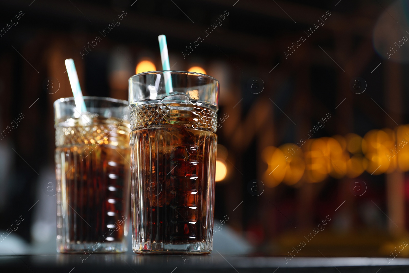 Photo of Glasses with refreshing cola and ice cubes on table indoors. Space for text