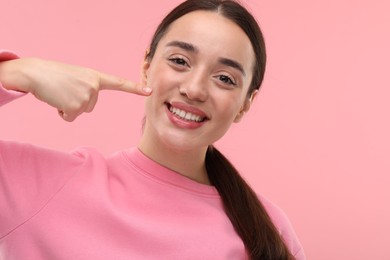 Photo of Beautiful woman showing her clean teeth and smiling on pink background, space for text