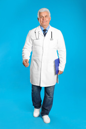 Photo of Senior doctor with clipboard walking on light blue background
