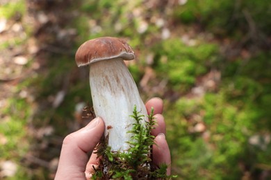 Photo of Woman holding porcini mushroom in forest, closeup
