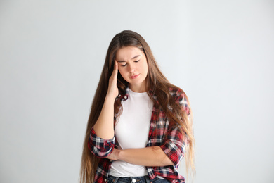 Photo of Young woman suffering from headache on light background