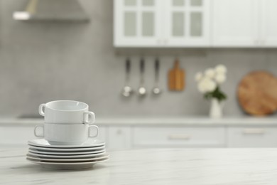 Photo of Clean dishware on white table in kitchen, space for text
