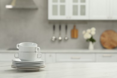 Photo of Clean dishware on white table in kitchen, space for text