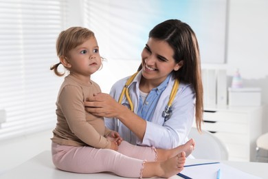 Photo of Pediatrician examining cute little baby in clinic