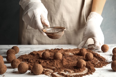 Photo of Woman preparing tasty chocolate truffles at table, closeup