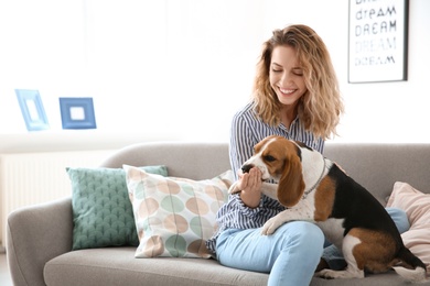 Photo of Young woman with her dog on sofa at home