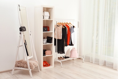Photo of Wardrobe with stylish bags and clothes indoors. Idea for interior design