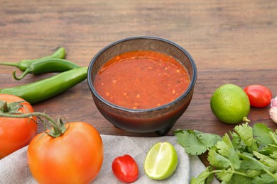 Photo of Tasty salsa sauce and different ingredients on wooden table