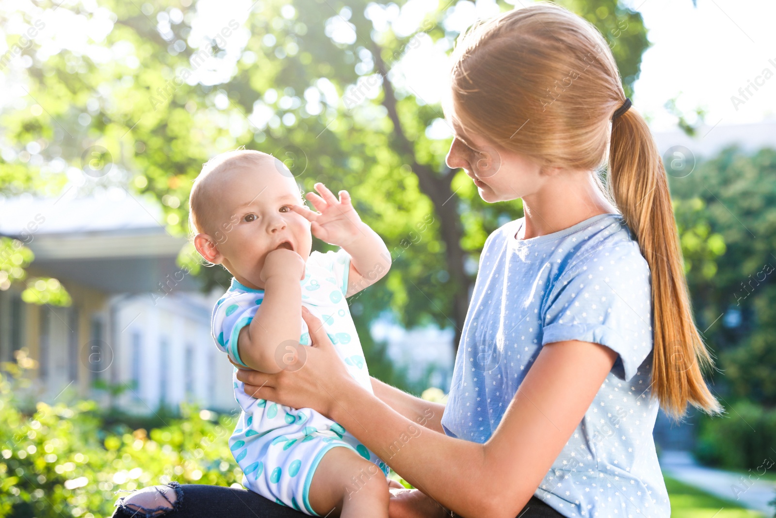 Photo of Teen nanny with cute baby outdoors on sunny day