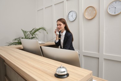 Photo of Beautiful receptionist talking on phone at counter in hotel