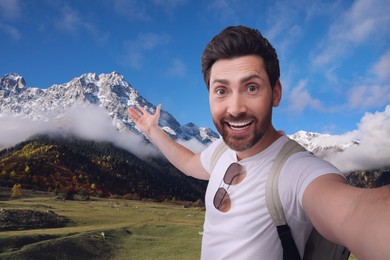 Image of Smiling man with camera taking selfie in mountains