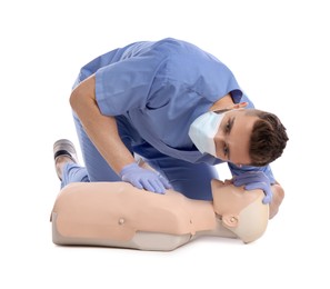 Photo of Doctor in uniform and protective mask practicing first aid on mannequin against white background