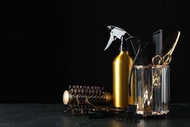 Photo of Different hairdresser tools on grey table against black background. Space for text
