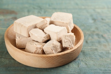 Photo of Plate with pieces of compressed yeast on blue wooden table