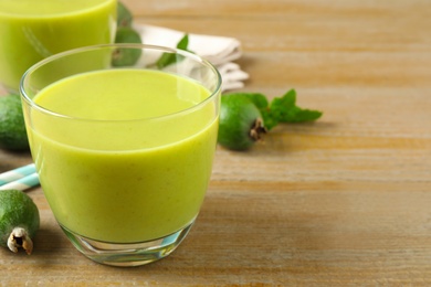 Photo of Fresh feijoa smoothie on wooden table, space for text