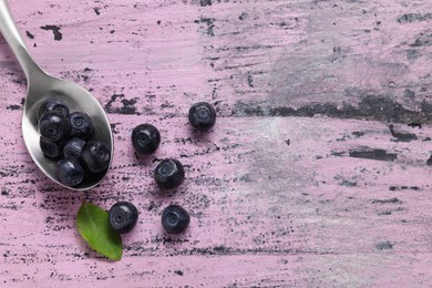 Photo of Ripe bilberries and leaf on wooden rustic table, flat lay. Space for text