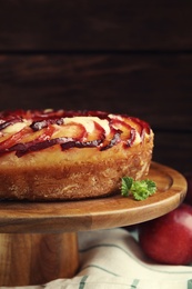 Photo of Delicious pie with plums on wooden cake stand, closeup