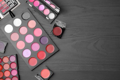 Photo of Colorful lipstick palettes on black wooden table, flat lay with space for text. Professional cosmetics