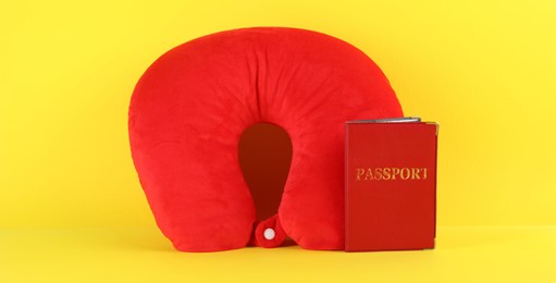 Photo of Red travel pillow and passport on yellow background