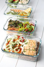 Photo of Healthy meal. Containers with different products on white wooden table