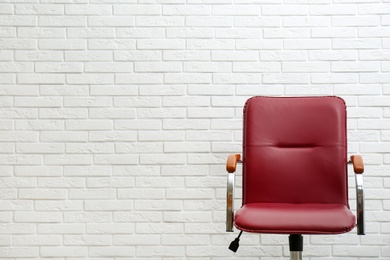 Photo of Comfortable office chair near white brick wall. Space for text