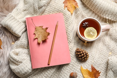Photo of Flat lay composition with book, cup of tea and warm sweater on fuzzy rug