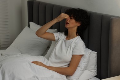 Photo of Young woman suffering from headache in bed at night