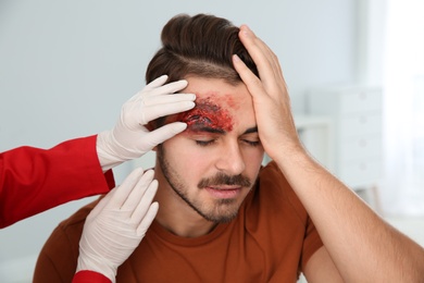 Photo of Nurse examining young man's head injury in clinic. First aid