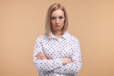 Photo of Portrait of sad woman with crossed arms on beige background