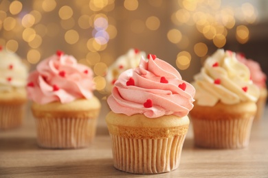 Photo of Tasty sweet cupcakes on wooden table. Happy Valentine's Day
