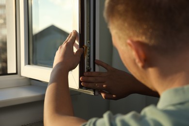 Photo of Construction worker putting sealing foam tape on window indoors, closeup