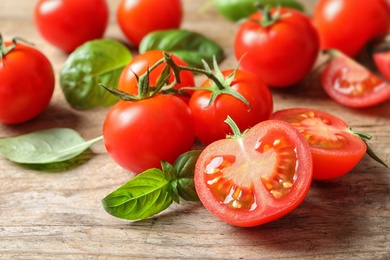 Photo of Fresh cherry tomatoes with basil on wooden background