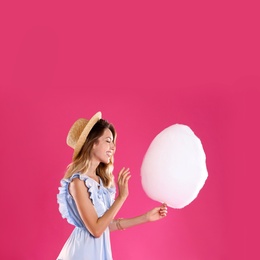 Photo of Happy young woman with cotton candy on pink background