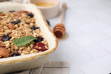 Photo of Tasty baked oatmeal with berries and almonds on white tiled table, closeup. Space for text