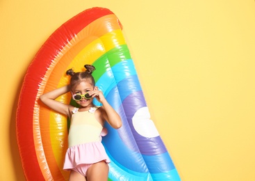 Photo of Cute little girl with inflatable mattress on color background