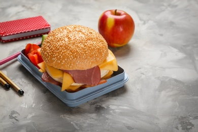 Photo of Lunch box with tasty sandwich and stationery on table