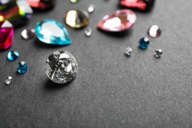 Photo of Different beautiful gemstones on black background. Space for text