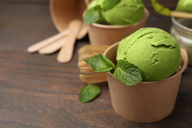 Photo of Paper cups with tasty matcha ice cream on wooden table, closeup. Space for text