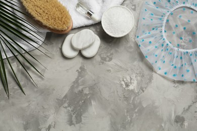 Photo of Flat lay composition with shower cap and toiletries on grey stone background. Space for text