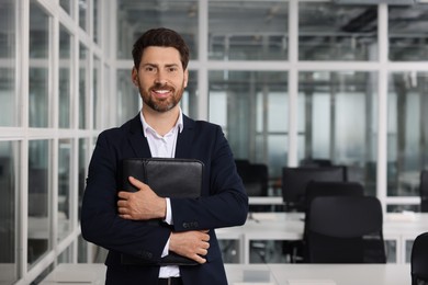Photo of Happy real estate agent with leather portfolio indoors. Space for text
