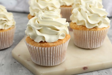 Photo of Tasty cupcakes with vanilla cream on grey table, closeup