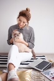 Photo of Young female blogger with laptop and cat indoors