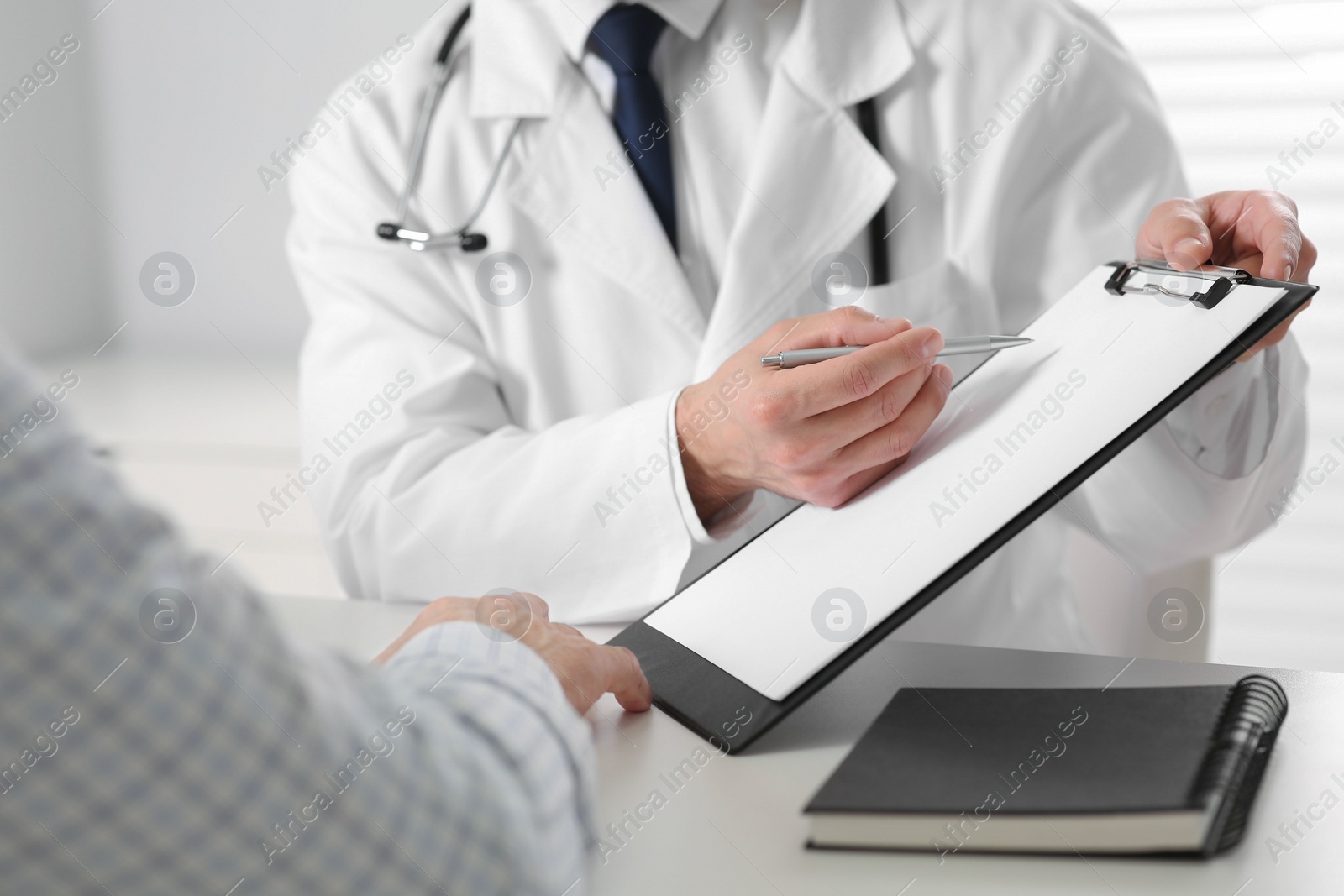 Photo of Doctor consulting senior patient at white table in clinic, closeup