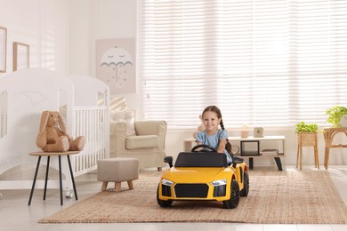 Photo of Adorable child driving toy car in room at home