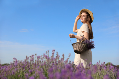 Photo of Young woman with wicker basket full of lavender flowers in field