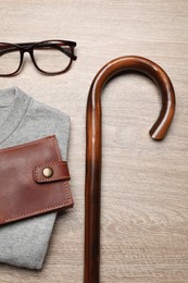 Photo of Stylish outfit with walking cane on wooden background, flat lay